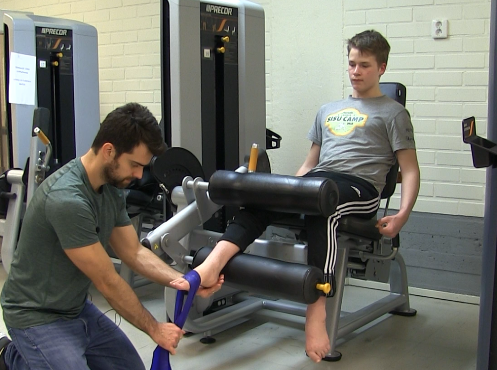 Valmentaja ohjaa nilkan koukistus-liikettä